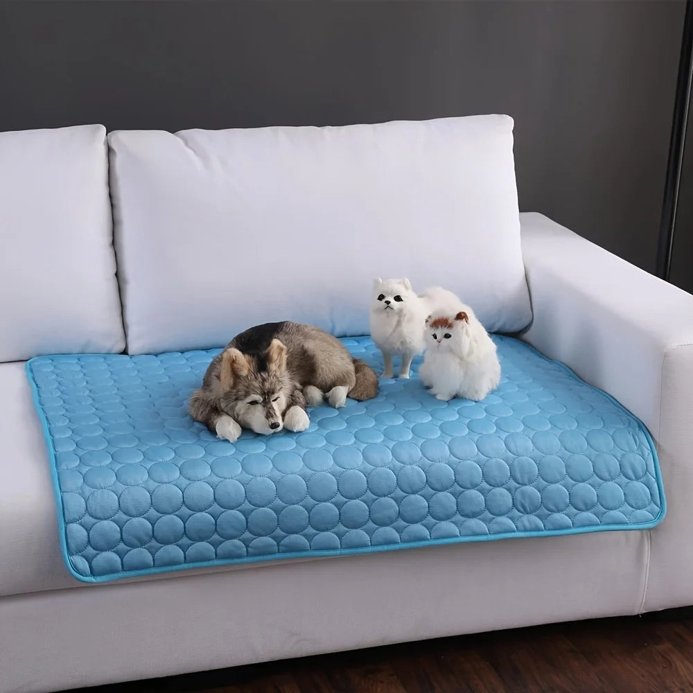 Blue pet mat on a white couch with plush toys on top. Summer dog cooling mat for large and small pets, breathable washable pet ice pad blanket for cats and dogs