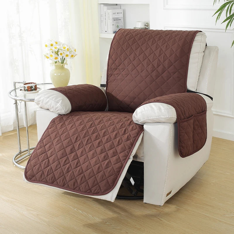 Brown quilted chair cover on a white recliner chair in a living room setting. Waterproof Recliner Sofa Cover with Side Pockets - Solid Color, Anti-Slip, Machine Washable Furniture Protector