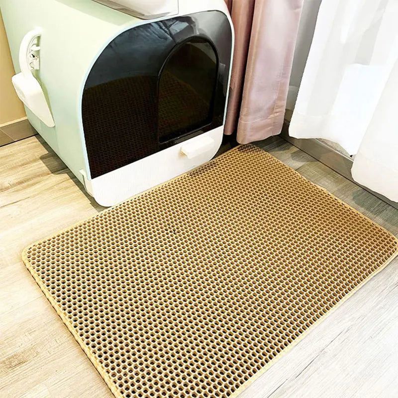 Cat litter box with a perforated mat on a wooden floor. Waterproof double-layer EVA cat litter mat for trapping loose litter and protecting floors